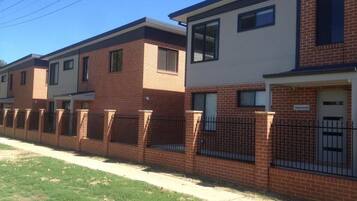 A row of townhouses with brick facades, a gated driveway, and a clear sky.