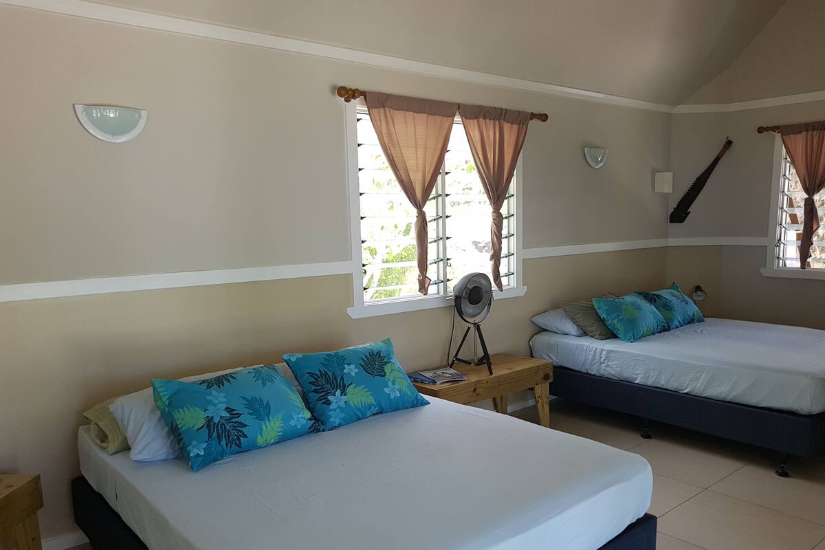 Un dormitorio con dos camas, un ventilador y una ventana con cortinas.