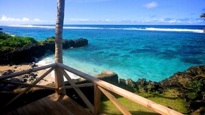 A wooden deck overlooking a turquoise ocean with clear waters and a palm tree. - Sa'Moana Beach Bungalows (Salamumu)