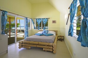 A room with a bed, a sliding glass door leading to a balcony, and a view of the ocean. - Sa'Moana Beach Bungalows (Salamumu)