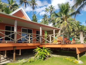 A two-story building with a red exterior and a balcony with wooden railings. - Sa'Moana Beach Bungalows (Salamumu)