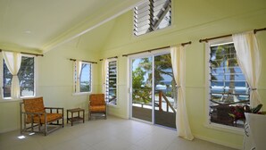 A spacious room with a large sliding glass door leading to a balcony, two chairs, and a small table. - Sa'Moana Beach Bungalows (Salamumu)