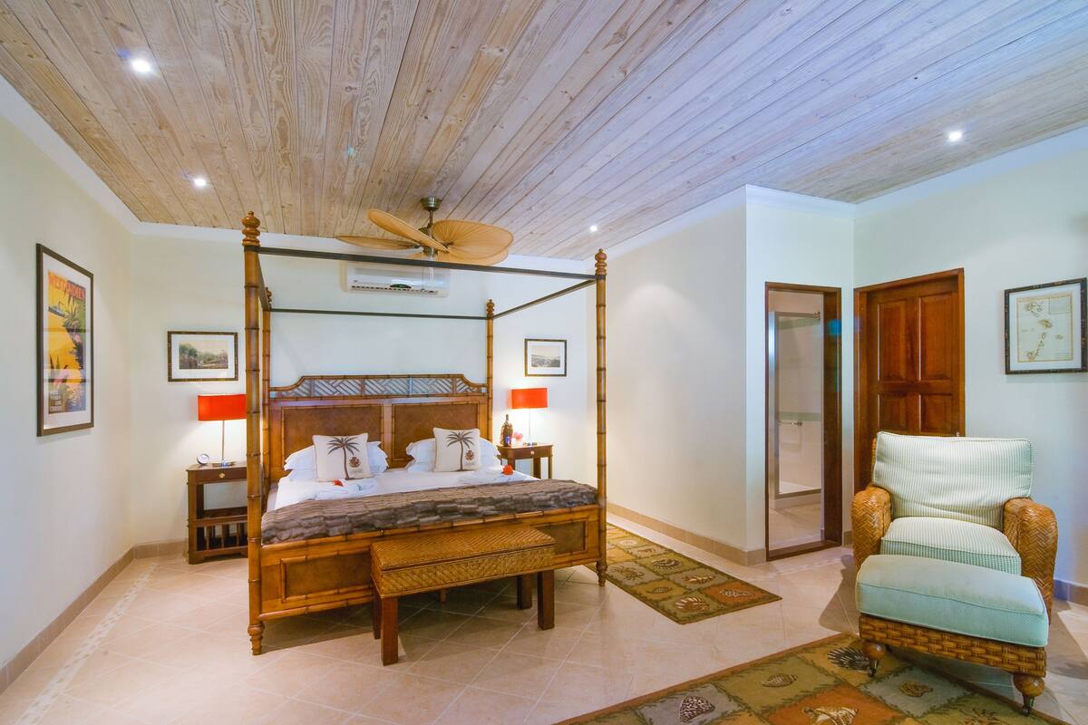 A four-poster bed with a wooden headboard, a ceiling fan, and a nightstand with a lamp.