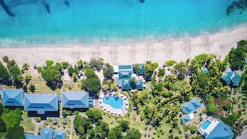 An aerial view of a resort with multiple buildings, a swimming pool, and a beach.