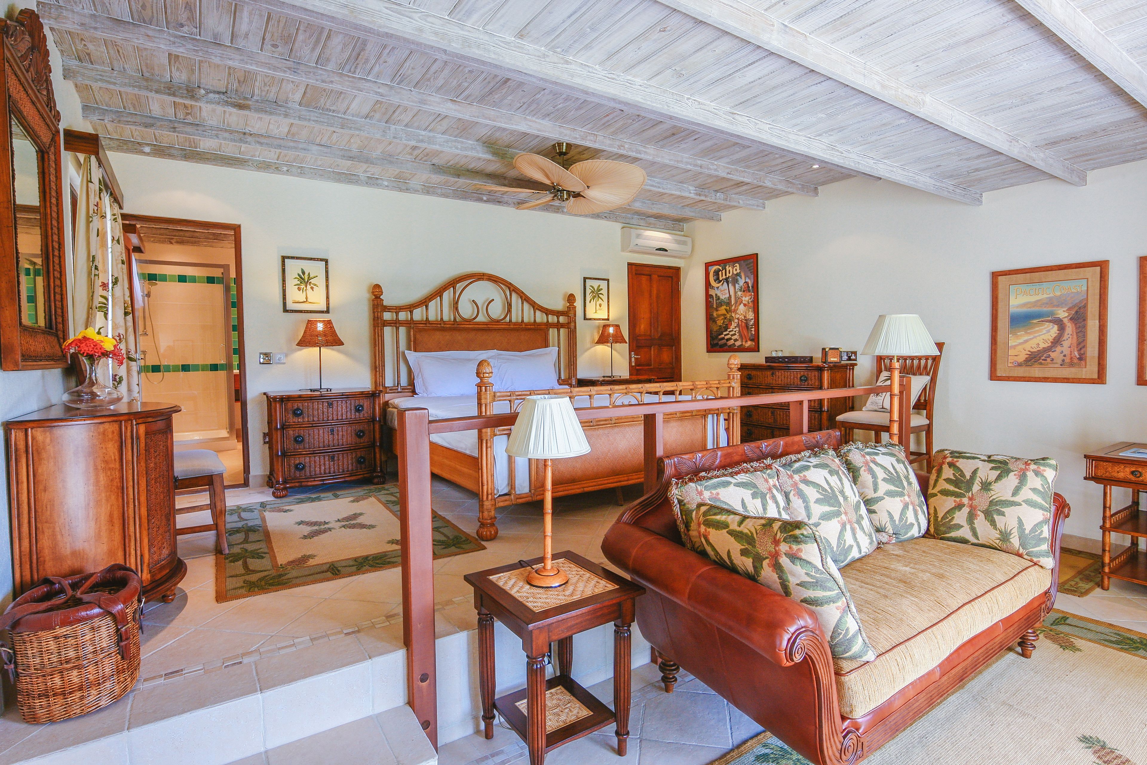 A spacious room with a wooden ceiling, a bed, a sofa, and a dining area.