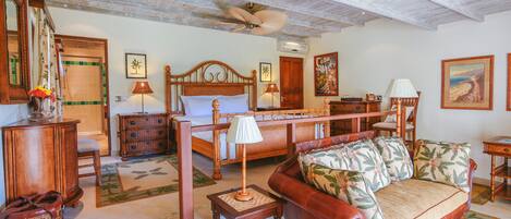 A spacious room with a wooden ceiling, a bed, a sofa, and a dining area.