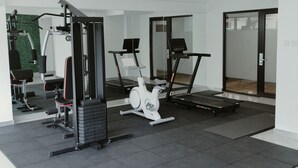 Une salle de sport moderne équipée de machines de cardio, d’appareils de musculation et dotée d’un mur entièrement recouvert de miroirs.