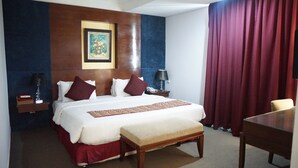 Une chambre d’hôtel avec un grand lit, une table de chevet avec une lampe, une petite table et une chaise.