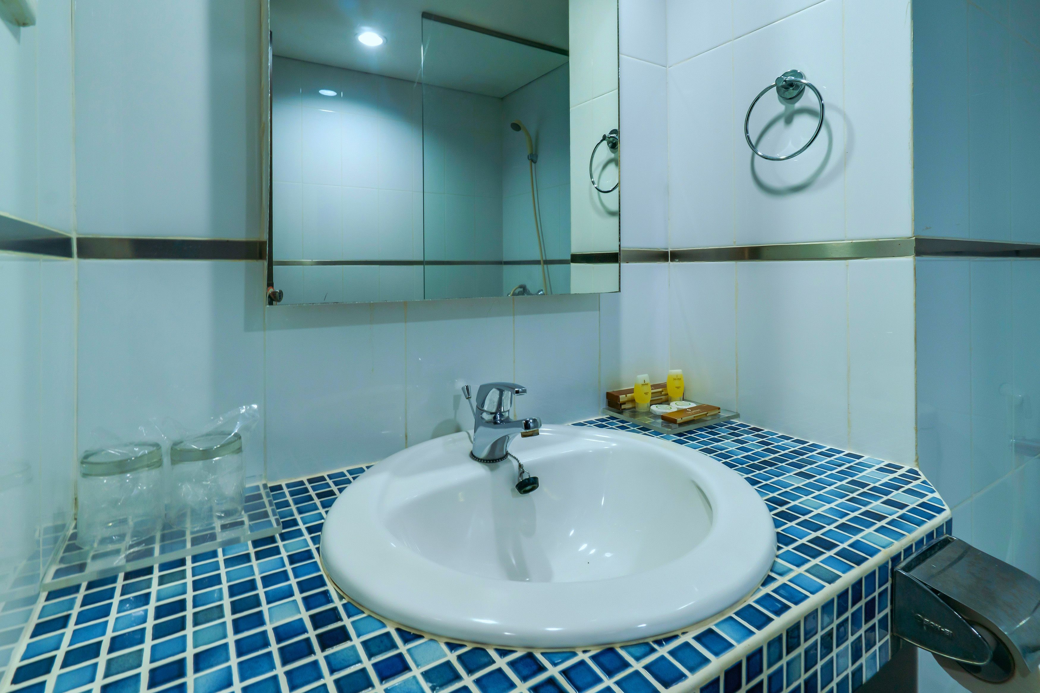 A bathroom with a white sink, blue-tiled countertop, and a mirror above the sink.