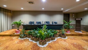 Une salle de conférence avec une longue table, de nombreuses chaises et plusieurs plantes en pot disposées autour de la table.