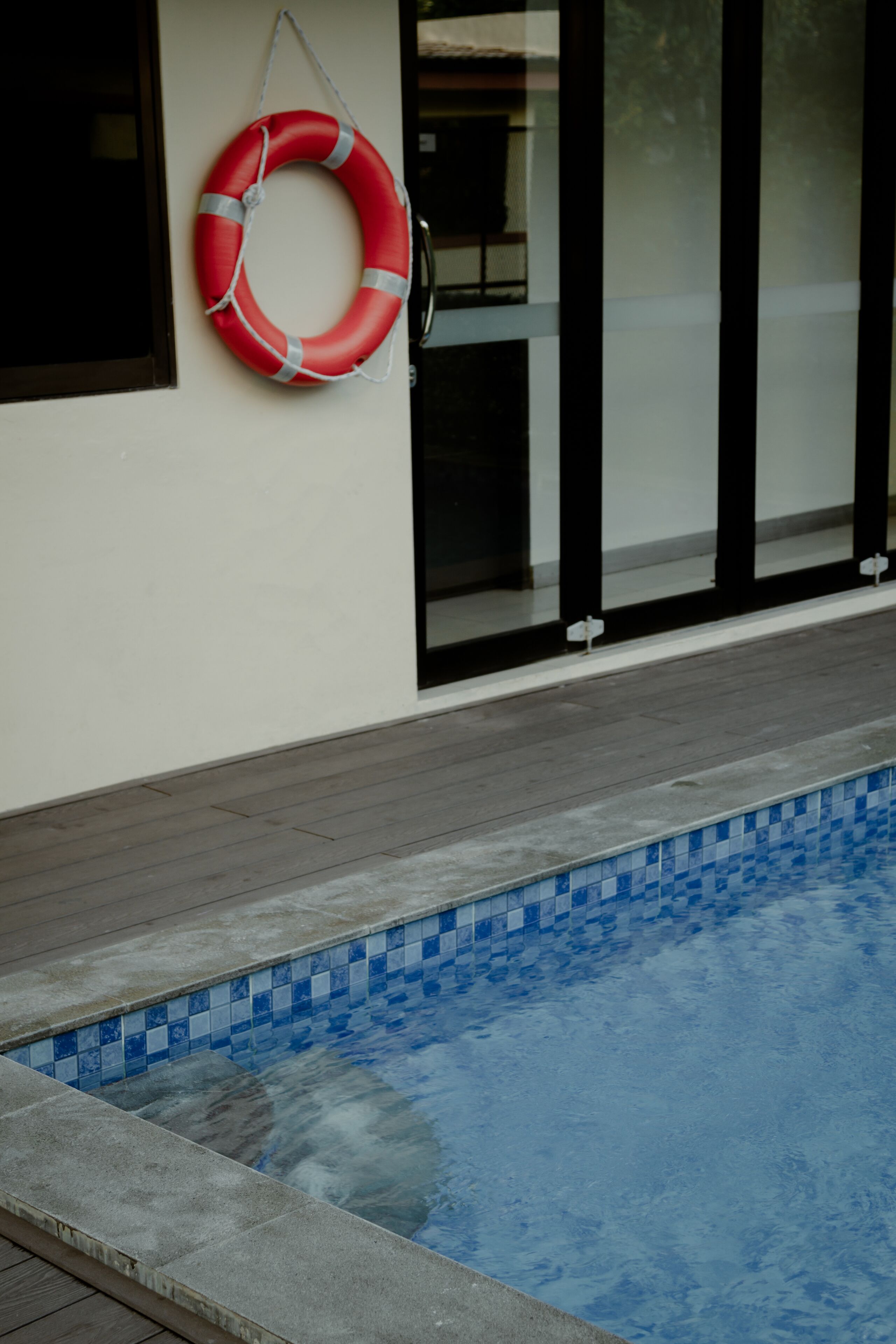 A swimming pool with a tiled edge and a red life ring hanging on the wall.