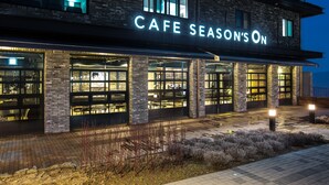 Un edificio con un cartel que dice "CAFE SEASON'S ON" y ventanas grandes.