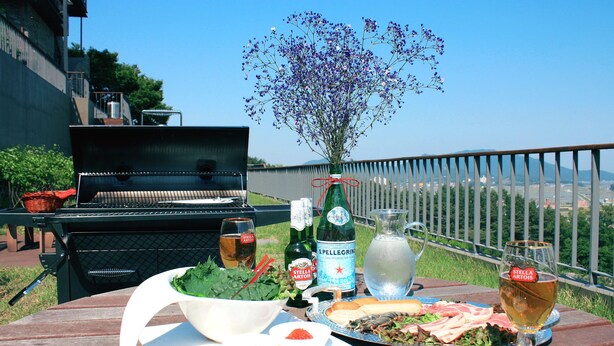 Una mesa de comedor con comida, una botella de cerveza Stella Artois, una botella de agua Pellegrino, un vaso de cerveza y un ramo de flores.
