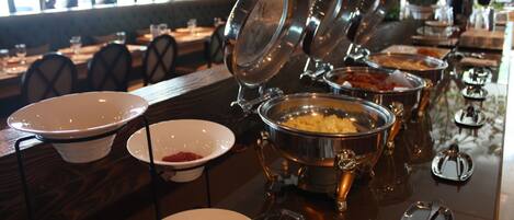 A buffet setup with multiple serving stations, including bowls and pots for food, arranged on a polished table.