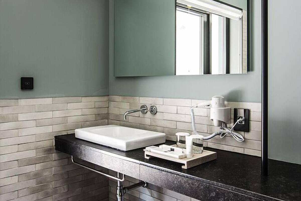 A modern bathroom with a white sink, black countertop, and a large mirror.