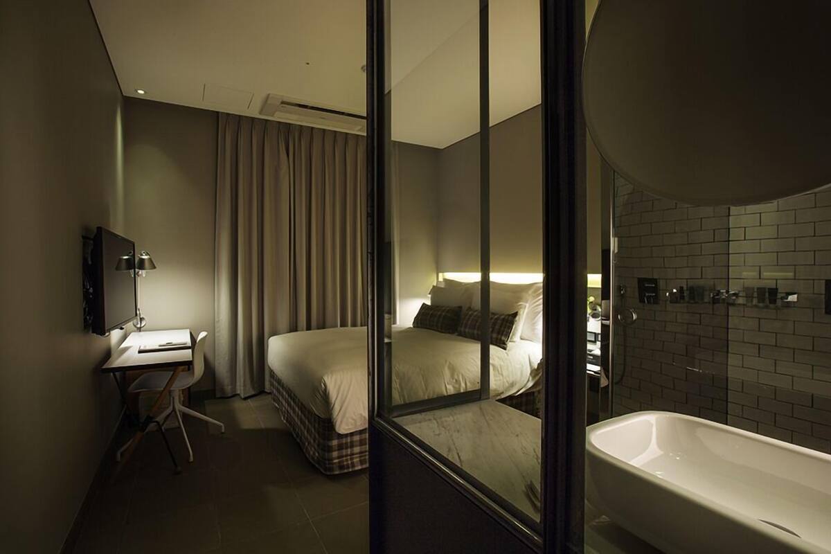 A modern hotel room with a large bed, a desk, and a separate bathroom area.