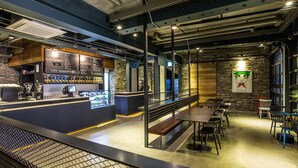 Un café moderno con barra, asientos y una pantalla mostrando el menú.