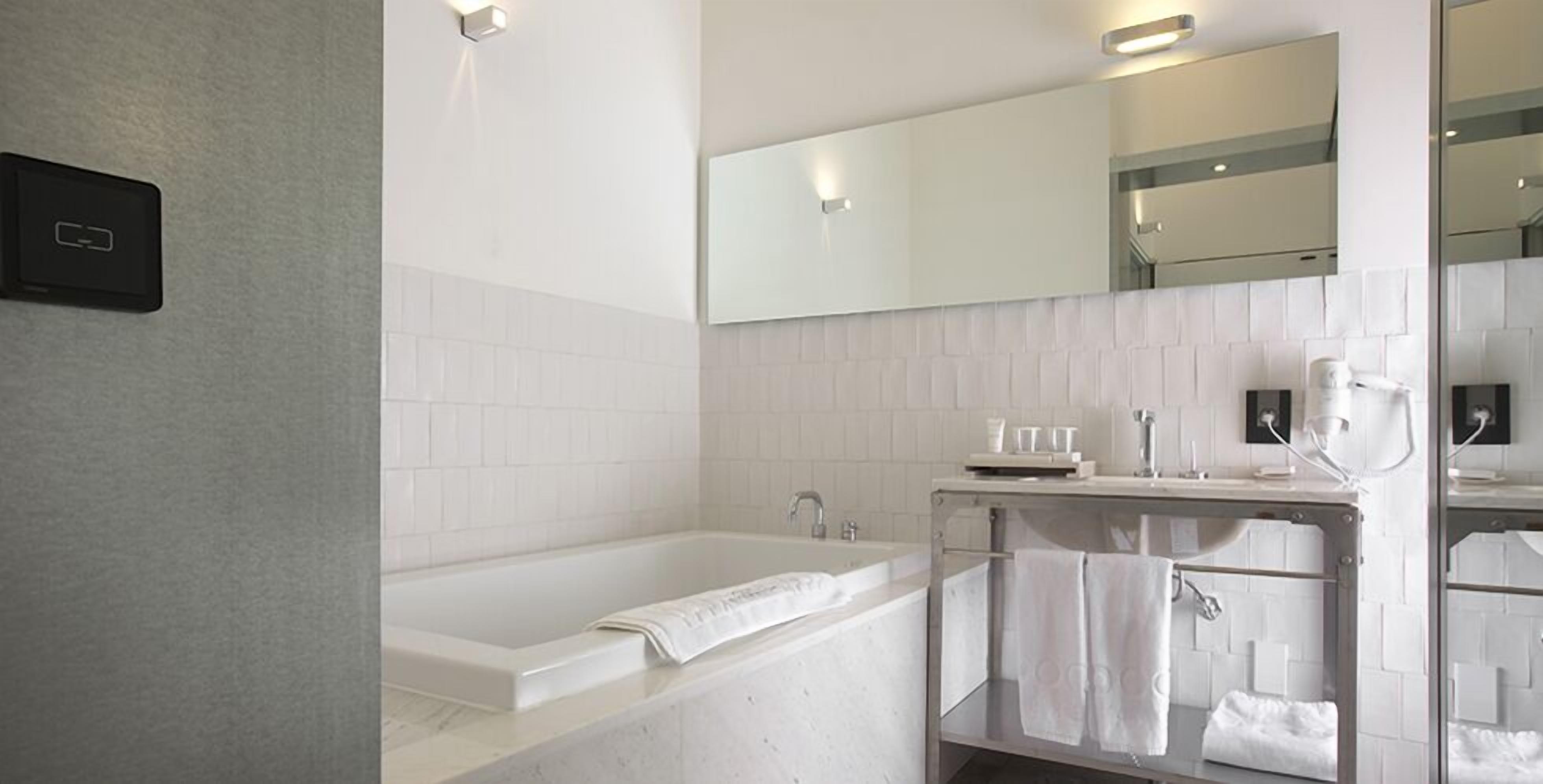 A modern bathroom with a bathtub, a vanity with a mirror, and a towel rack.