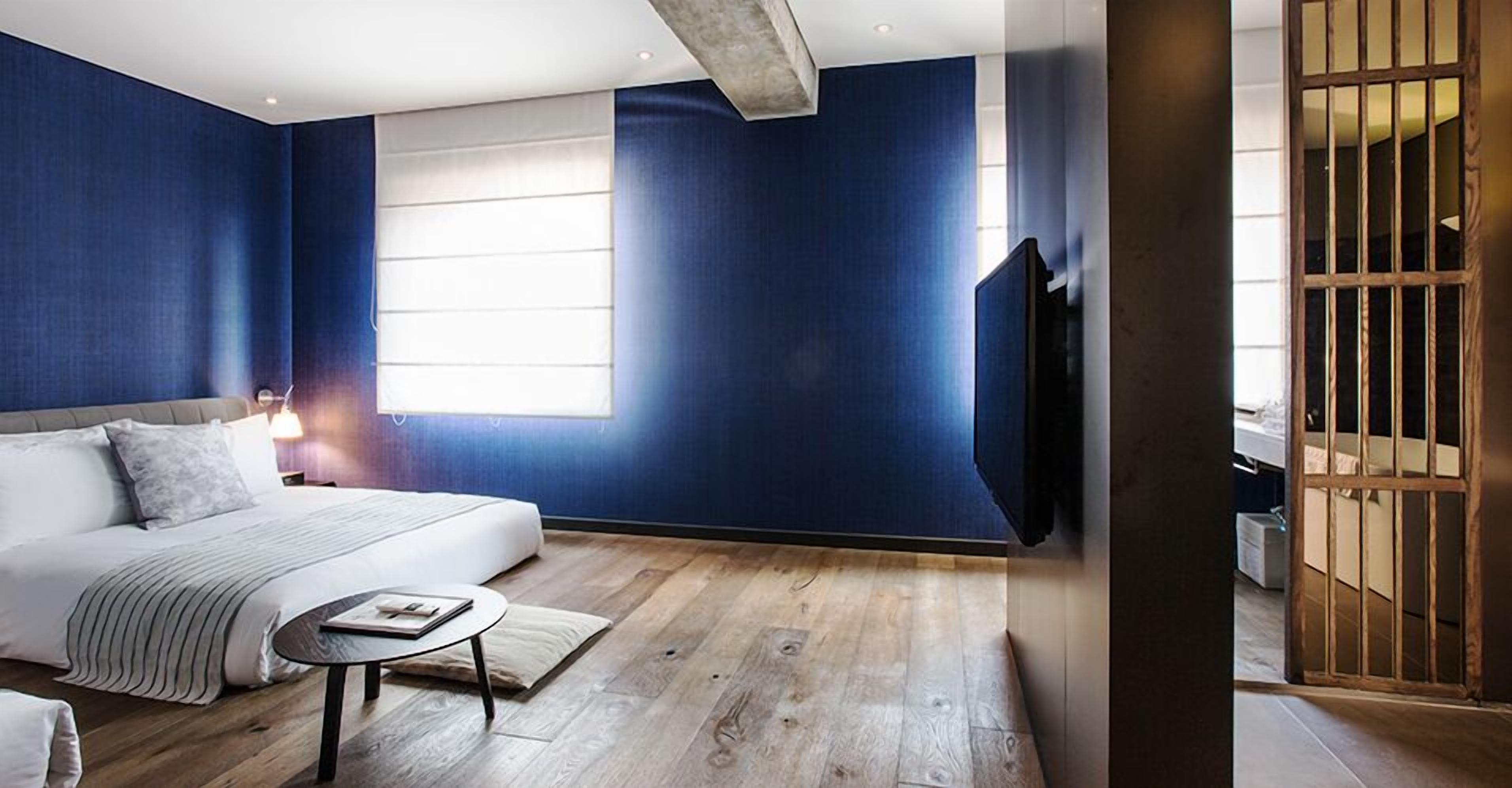 A modern bedroom with a large bed, a bedside table, and a TV mounted on the wall.
