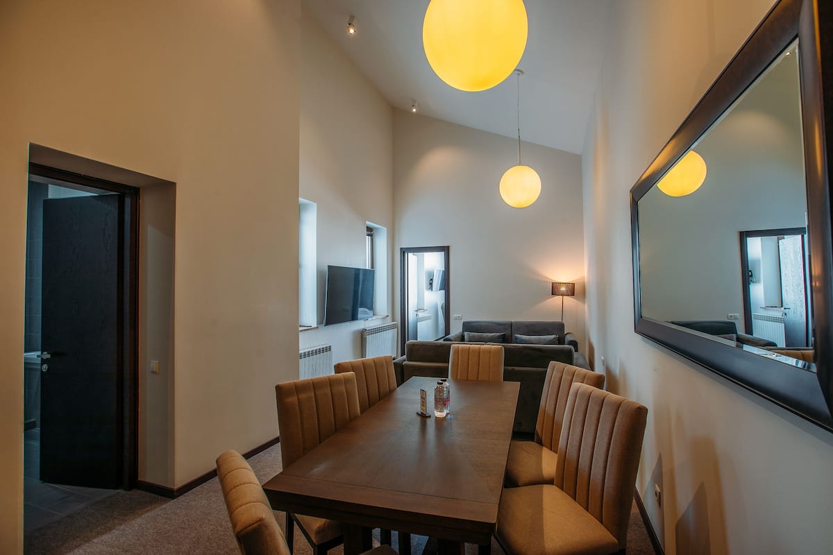 Una habitación de hotel moderna con comedor, sofá y un espejo grande.
