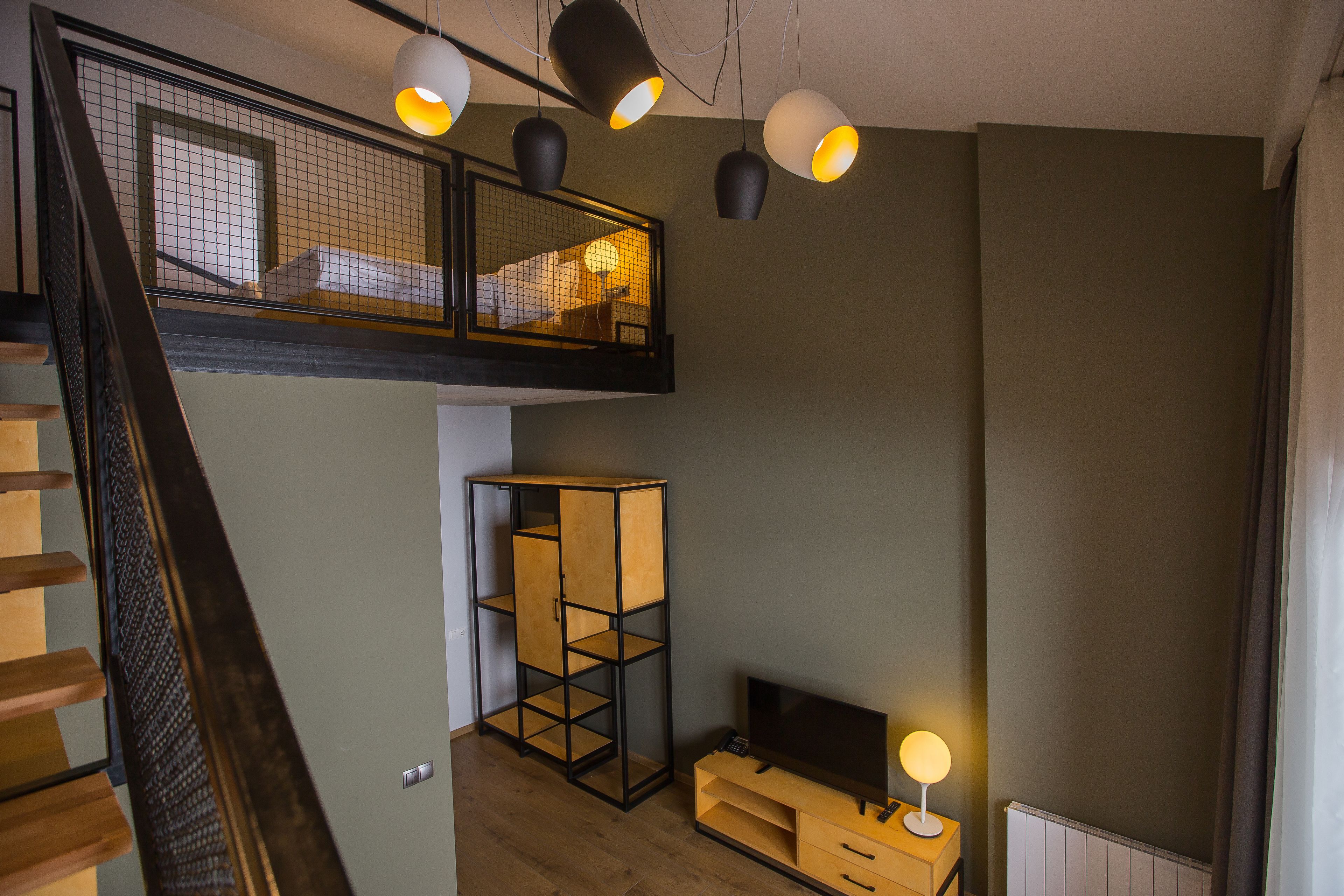 Un dormitorio estilo loft moderno con entrepiso, un armario de madera, un televisor y una escalera.