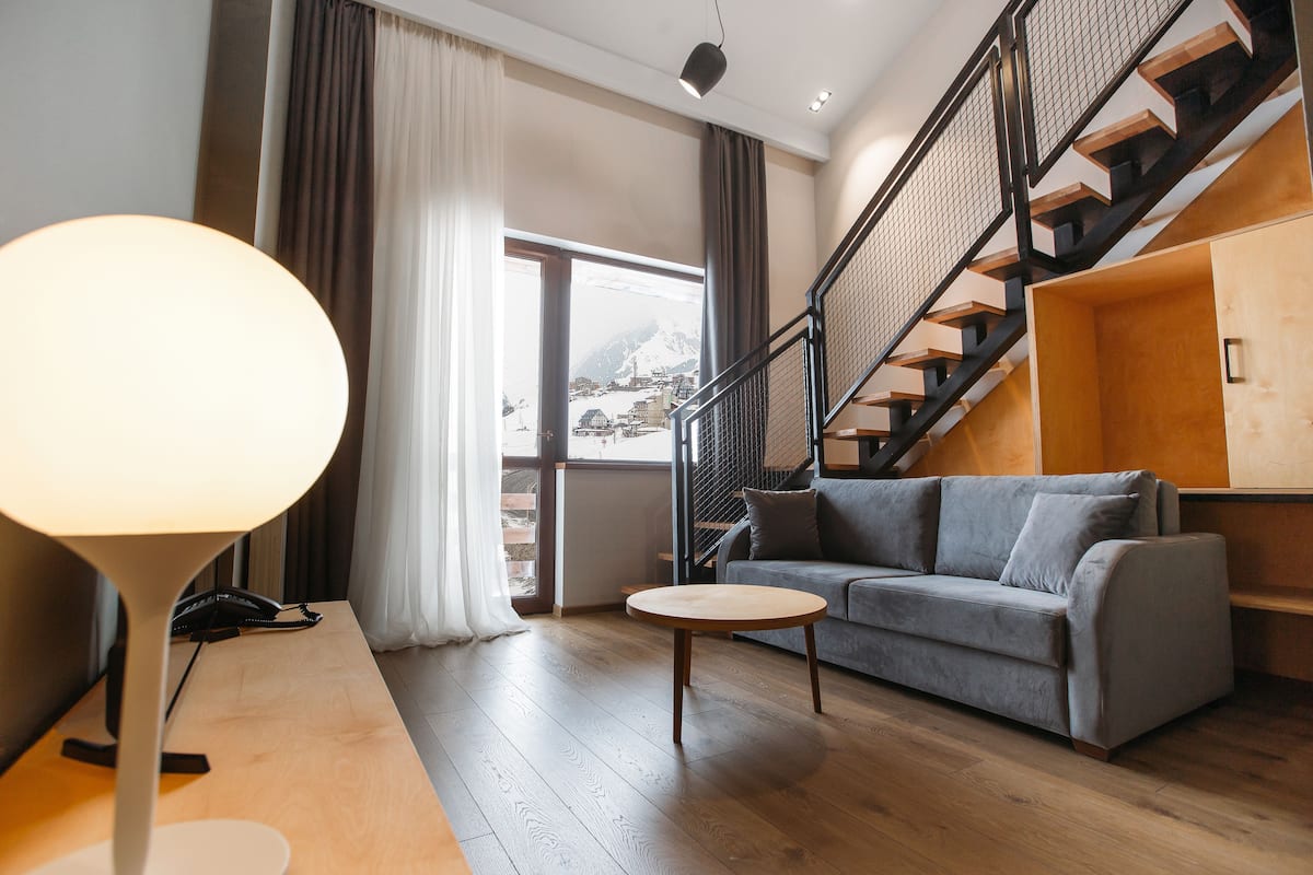 Una sala de estar moderna con sofá, una mesa de centro, una lámpara y una escalera.