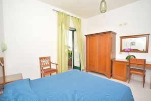 A bedroom with a bed, a wooden wardrobe, a desk with a chair, a mirror, and a window with curtains. - Hotel Maronti (Barano d'Ischia)