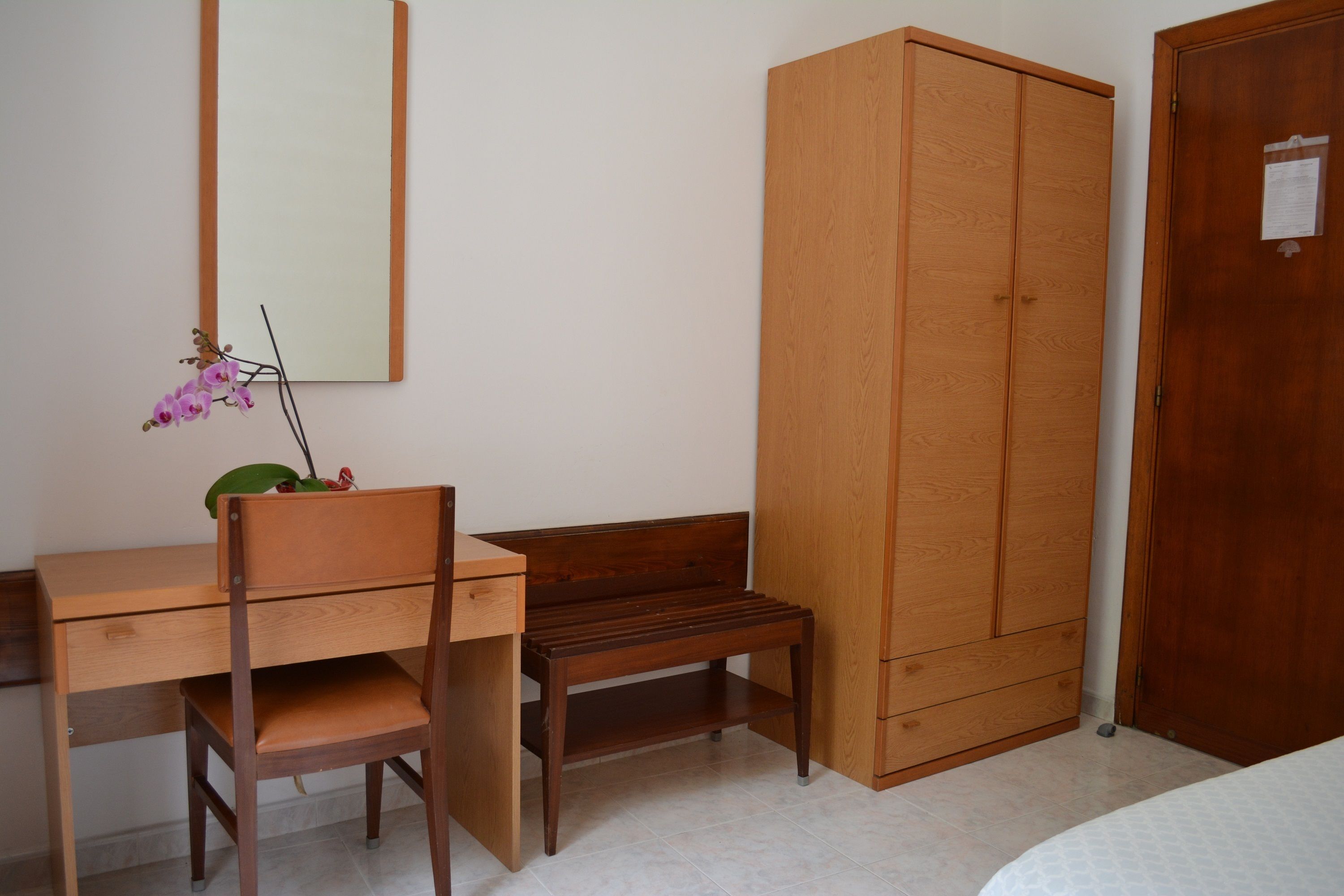 A bedroom with a wooden desk, chair, and wardrobe.