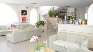 A spacious living area with a sofa set, a coffee table, and a staircase leading to an upper floor. - Hotel Maronti (Barano d'Ischia)