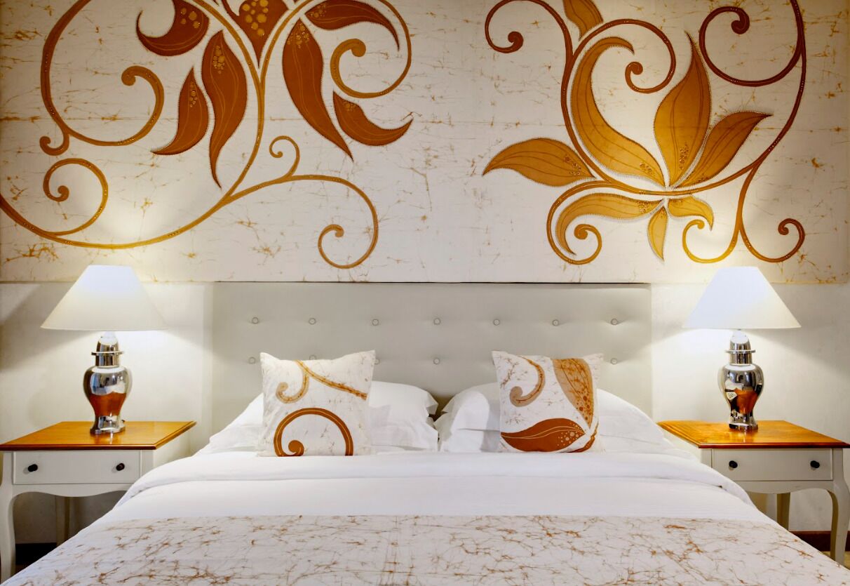 A hotel room with a large bed, two bedside tables with lamps, and a decorative wall design.