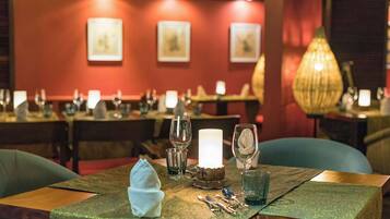 Een restaurantinterieur met gedekte tafels, met een groene tafelkleed, kaarsen en glazen.