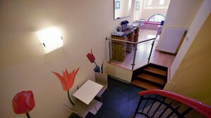 Eine Treppe führt zu einem Essbereich mit Tisch und Stühlen, einem Heizkörper und einer Wandleuchte.