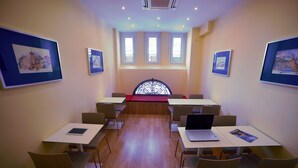 Ein Konferenzraum mit Tischen, Stühlen und gerahmten Kunstwerken an den Wänden.