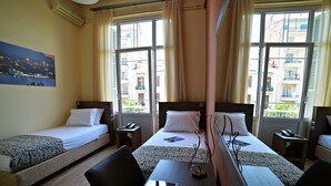 Ein Hotelzimmer mit zwei Einzelbetten, einem Schreibtisch mit Stuhl und einem großen Fenster mit Vorhängen.