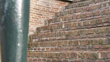 Un escalier en briques, avec une rampe métallique en premier plan.