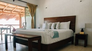 Una habitación de hotel con una cama, una mesita de noche de madera, una pequeña mesa y una silla.