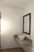 Un baño con lavamanos blanco, encimera de granito y espejo con marco de madera.
