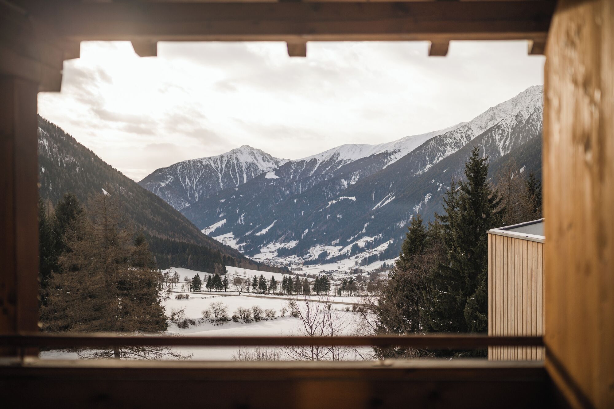 Vista des d'una finestra sobre una vall coberta de neu i muntanyes.