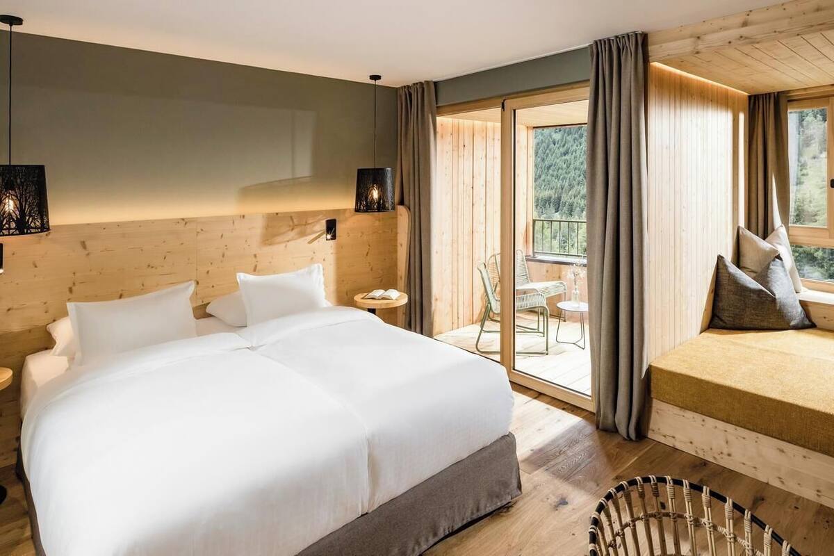 Une chambre dotée d’un grand lit, d’un canapé-lit plus petit, d’une fenêtre avec des rideaux et offrant une vue sur l’extérieur.