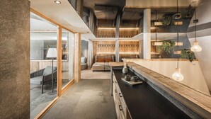 A modern interior with a central seating area, a long counter, and a mix of natural and artificial lighting. - Falkensteiner Hotel Antholz (Rasun Anterselva)