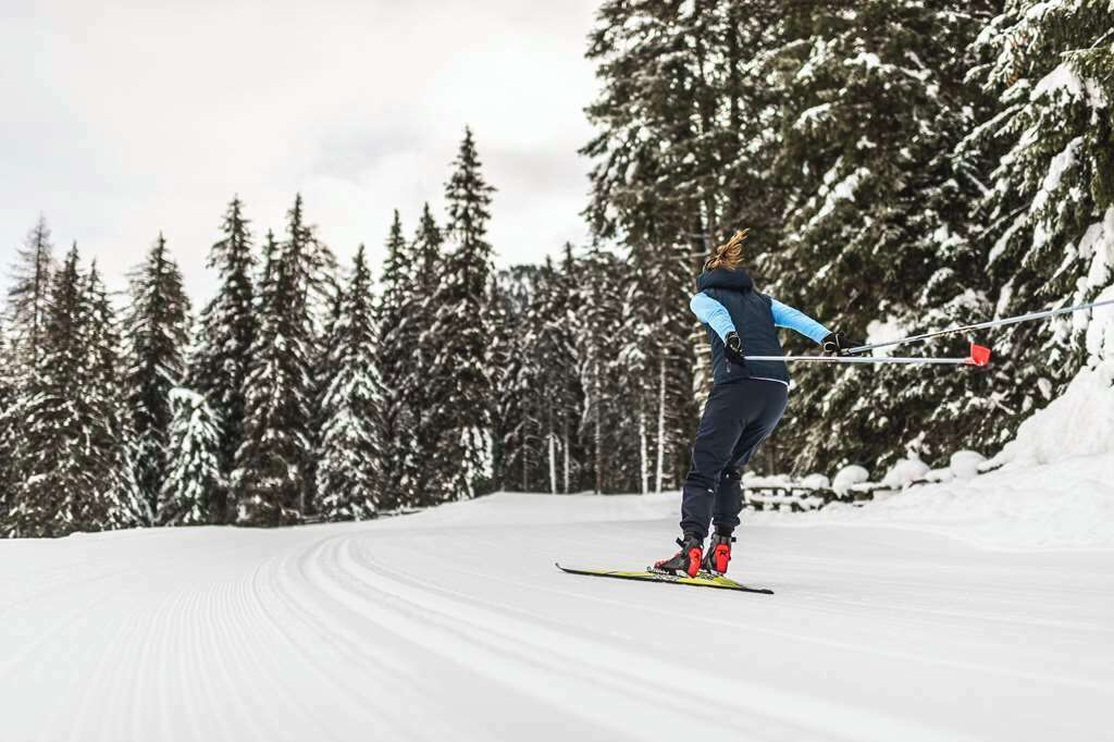 A person skiing on a snow-covered slope with trees in the background.