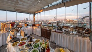 A buffet setup with various food items and condiments on tables, overlooking a cityscape. - Pera Center Hotel (Istanbul)