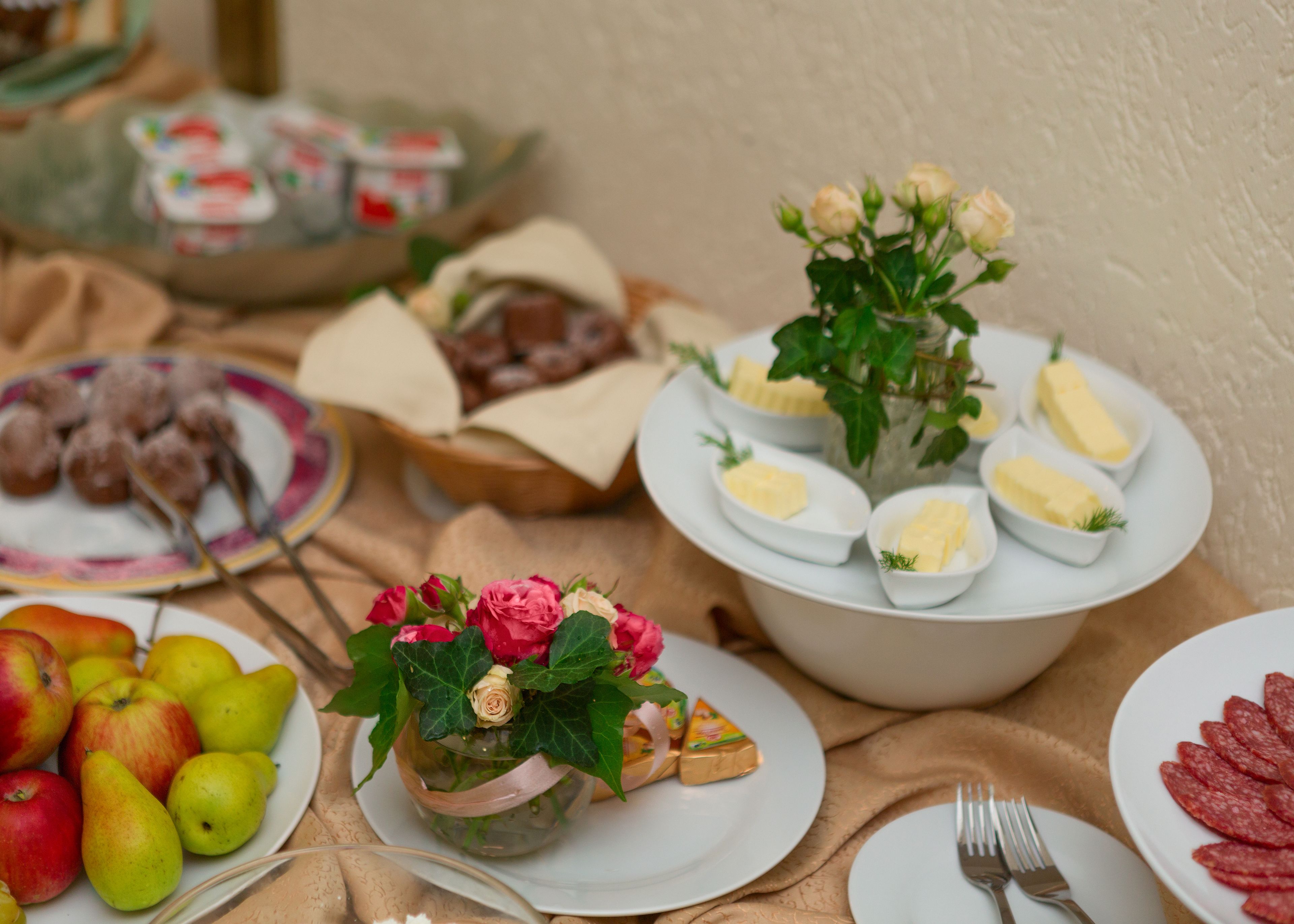 A buffet table with various food items including fruits, pastries, and a floral centerpiece.