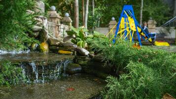 A small waterfall in a park with rocks and greenery.