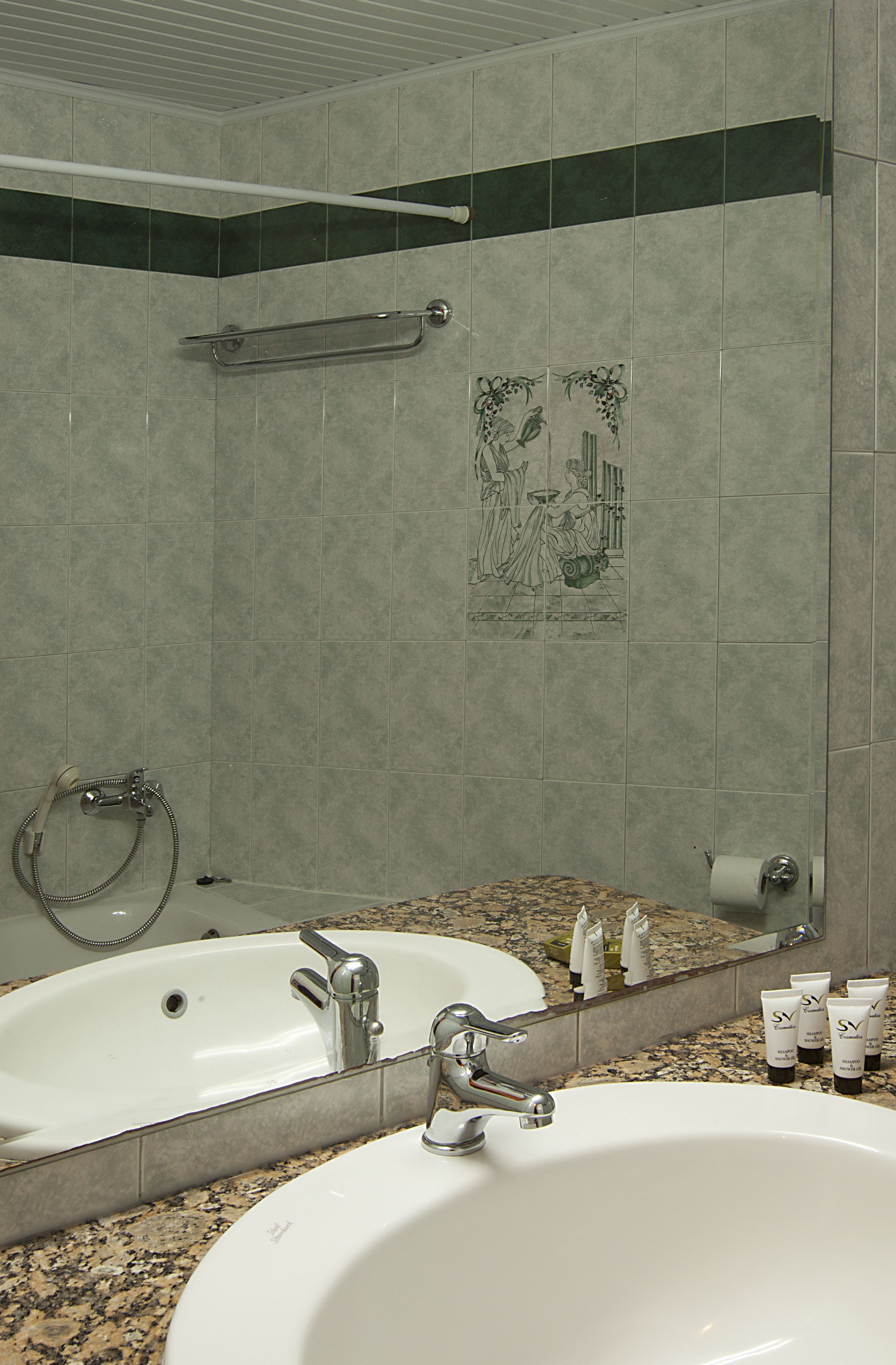 A bathroom with a large sink, mirror, and shower area.