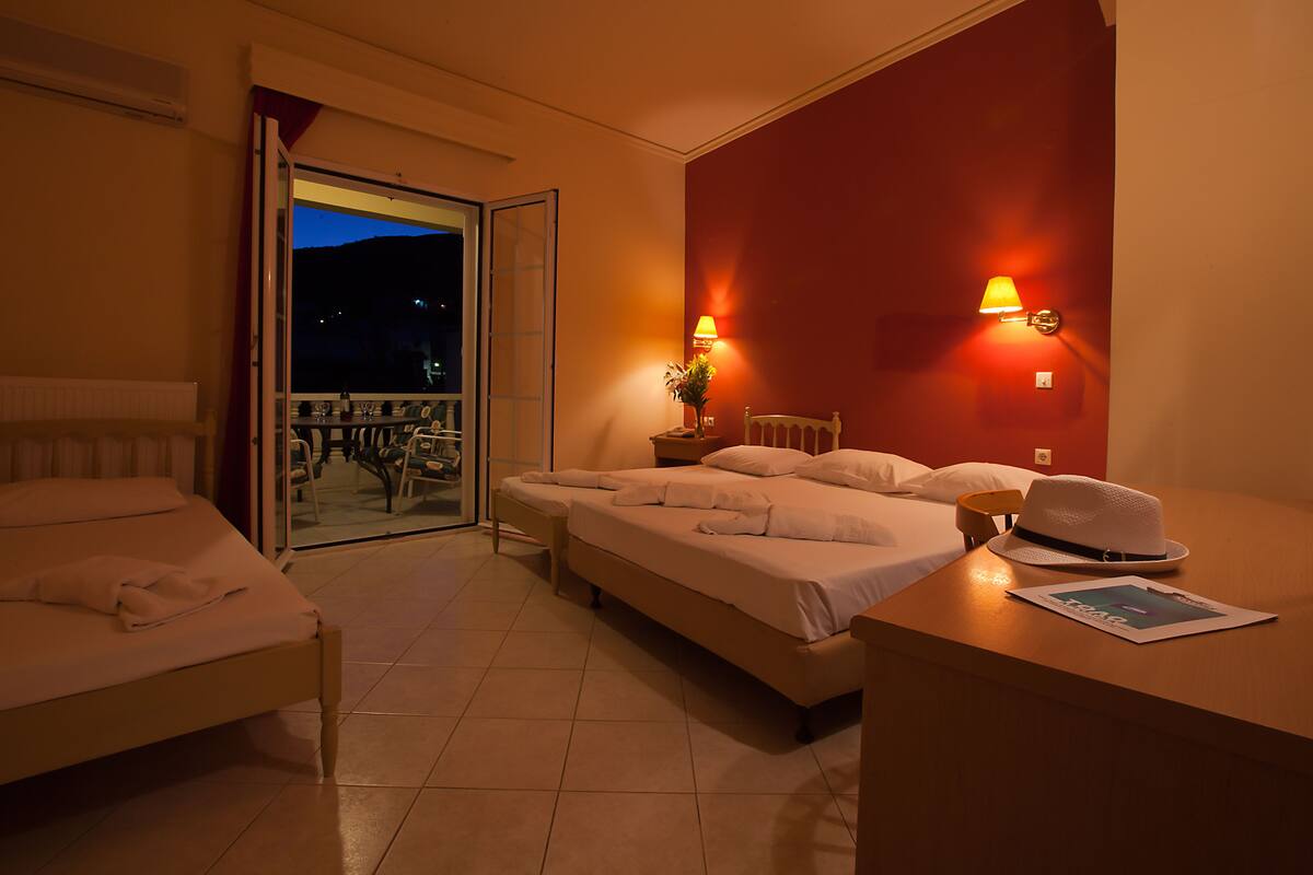 A hotel room with two beds, a balcony with a view, and two wall-mounted lamps.