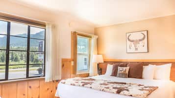 Quarto com uma cama grande, janela com vista para montanhas e uma obra de arte com caveira de boi na parede.