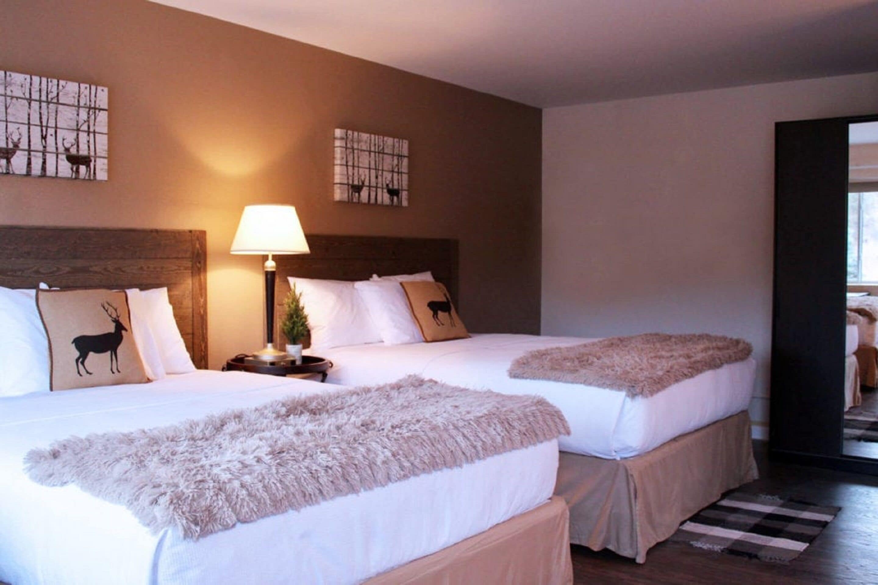 A hotel room with two beds, each with a headboard, a bedside table with a lamp, and decorative pillows.