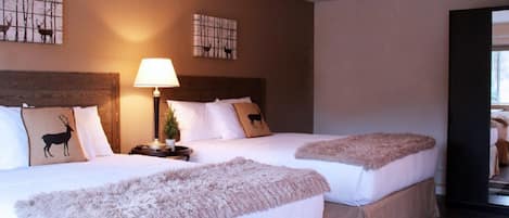 A hotel room with two beds, each with a headboard, a bedside table with a lamp, and decorative pillows.