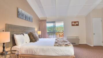 A hotel room with a large bed, a view of the outdoors, a balcony, and a mounted artwork.